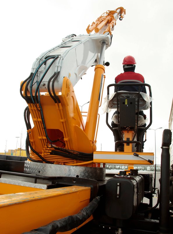 Operator running heavy hydraulic crane attachment on job site
