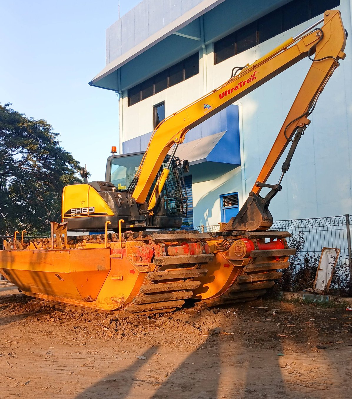 Yellow excavator with hydraulic breaker attachment at job site