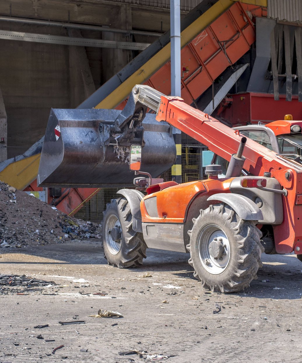 Telehandler moving debris at a concrete recycling facility